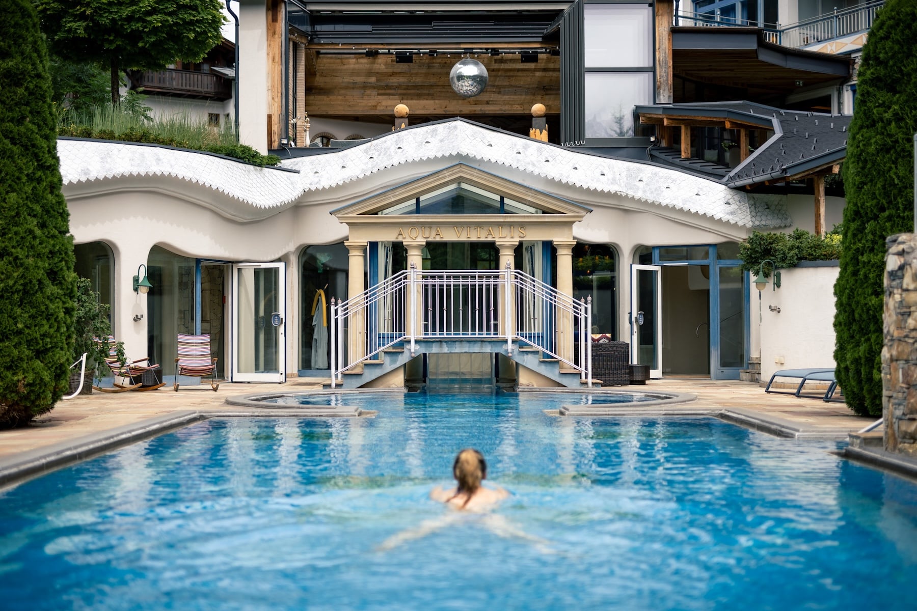Frau schwimmt im Pool mit Discokugel im Hintergrund