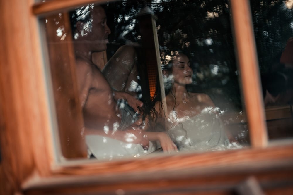 Couple enjoying the warmth of the log cabin sauna in the garden of Hotel Sendlhofer's in Bad Hofgastein