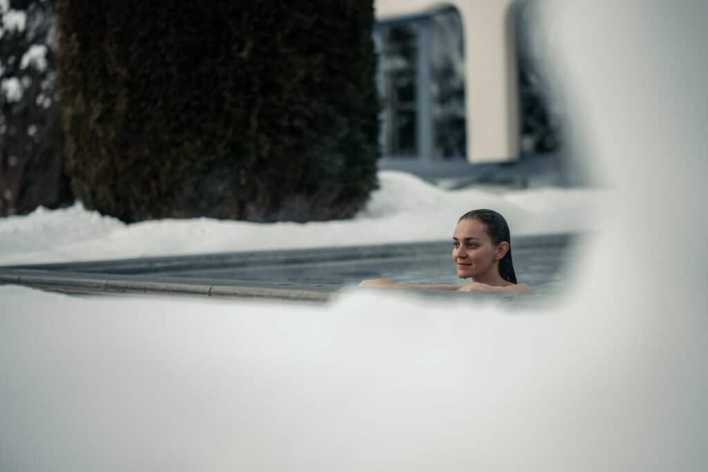 Women in the pool warm thermal pool enjoying the snow covered garden with Mountain View