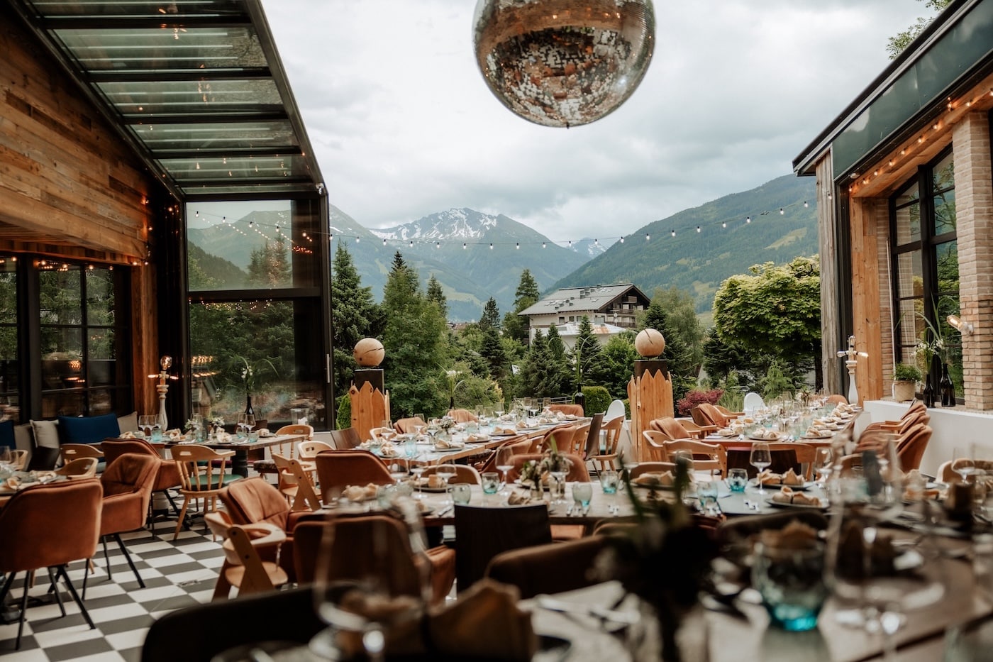 Wintergarten WeitBlick mit offener Glasfront eingedeckt für das Hochzeitsdinner mit Discokugel und Bergpanorama