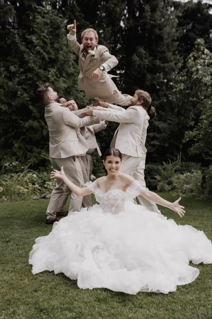 Braut, Bräutigam und Freunde des Bräutigams werfen Bräutigam in die Luft für Shooting