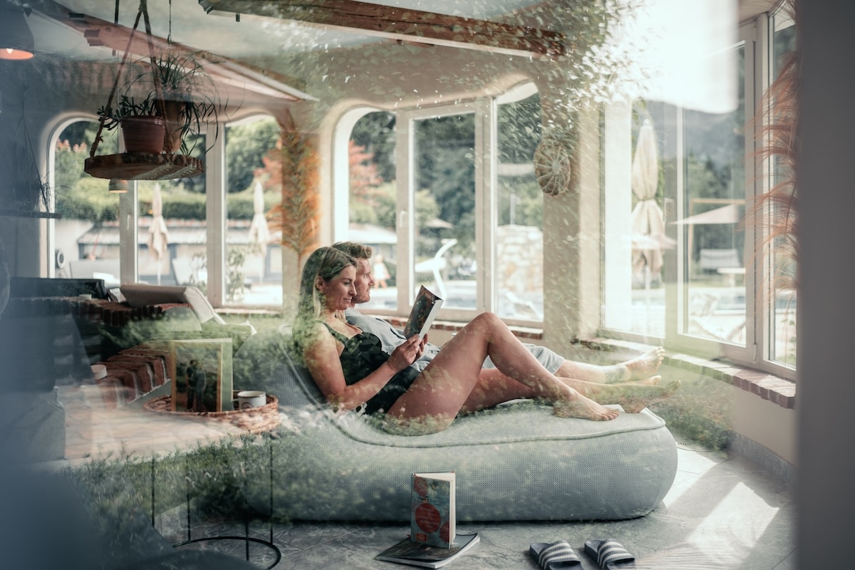 Pärchen im Ruheraum beim Lesen mit Blick in den Garten