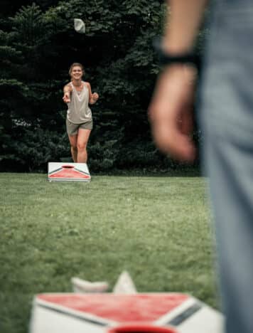 Zwei Frauen beim Corn Whole spielen im Garten