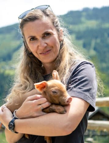 Eva mit kleinem Schweinchen auf dem Arm bei Besuch der Metzgerei